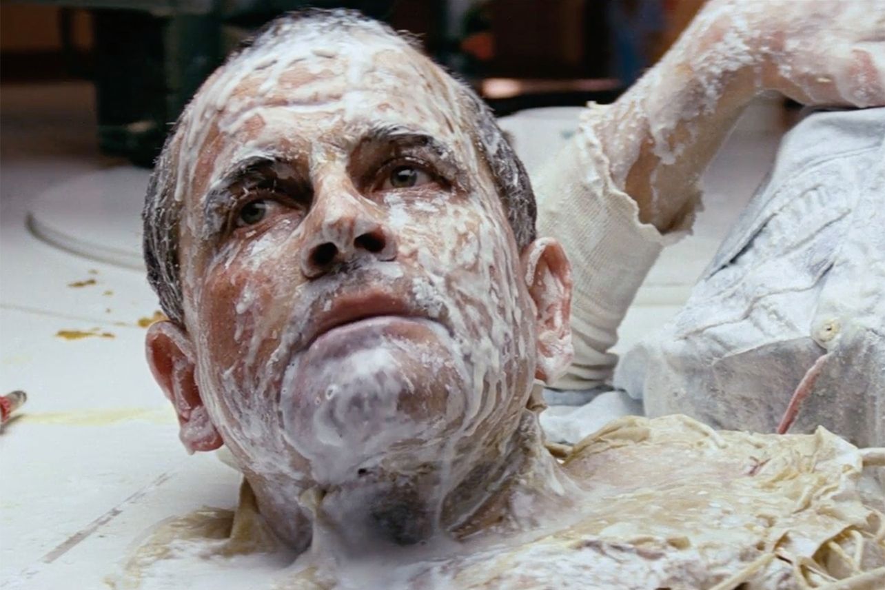 A still from Alien. A humanistic android, covered in milk, looks off frame.
