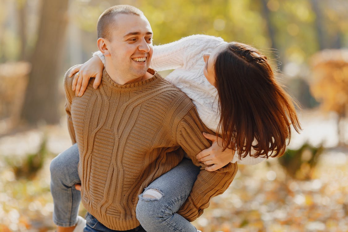 Happy adult couple walking in park in autumn