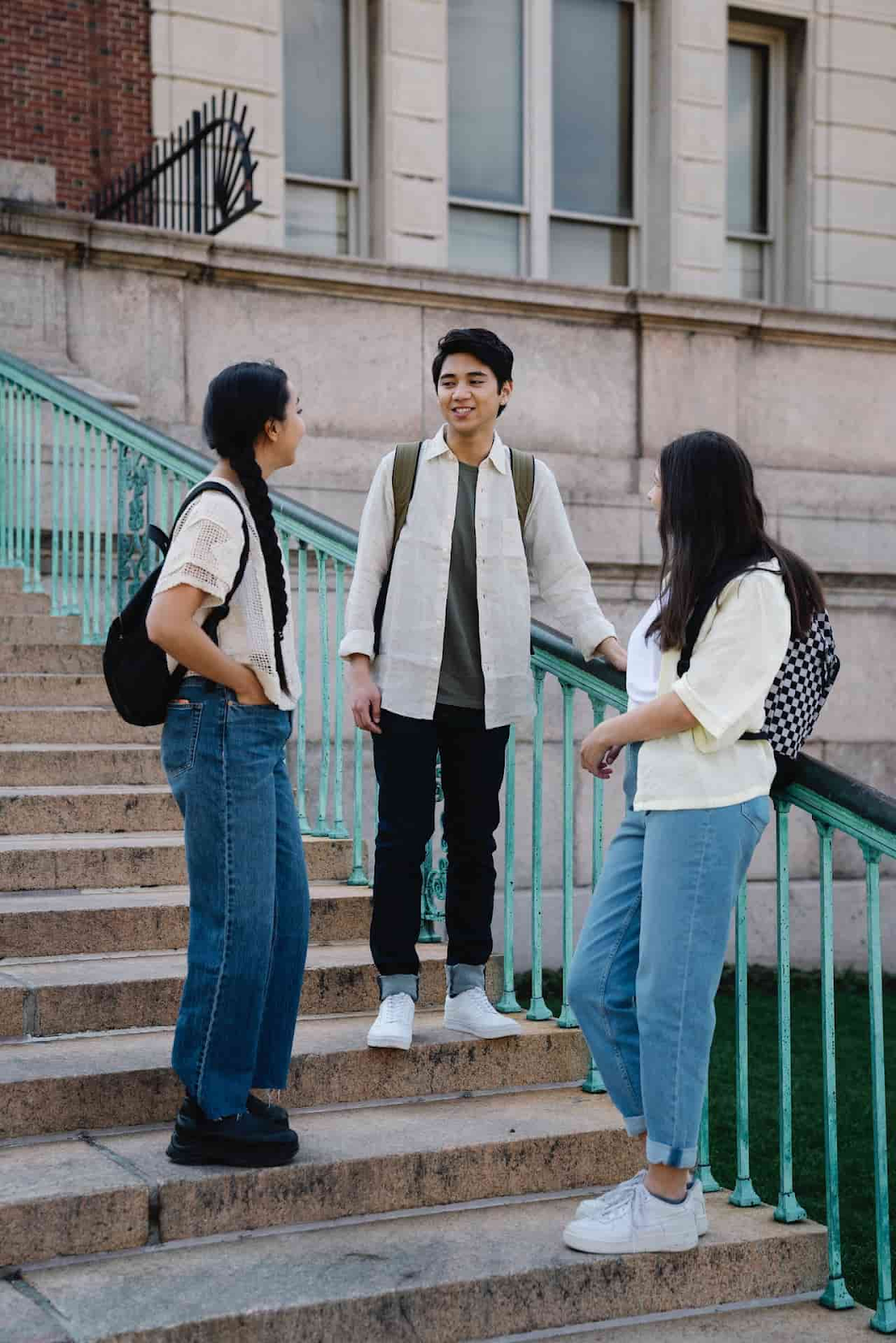 three (3) students socialize on campus stairs