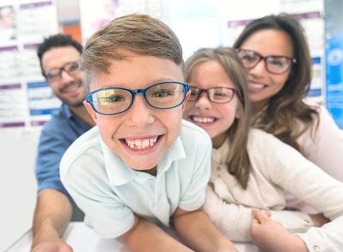 Happy Boy Trying Glasses At The Optical Shop With His Family Stock Photo -  Download Image Now - iStock