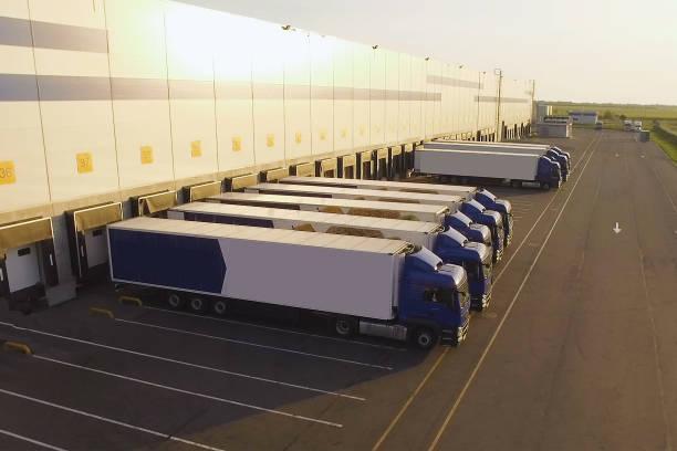 distribution warehouse with trucks awaiting loading distribution warehouse with trucks awaiting loading. shipping container storage stock pictures, royalty-free photos & images