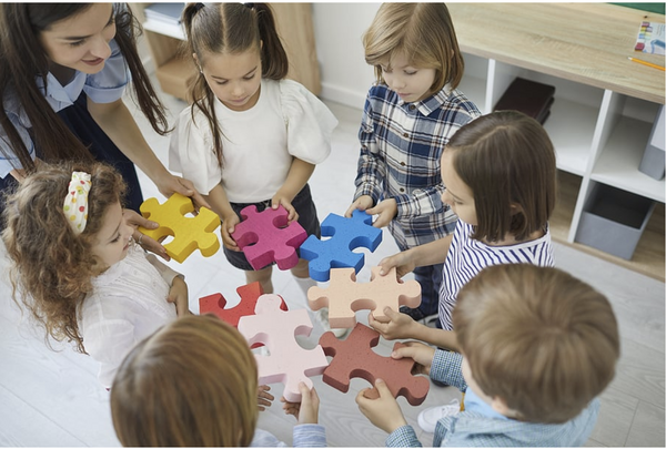 Preschool teacher helping children play with blocks