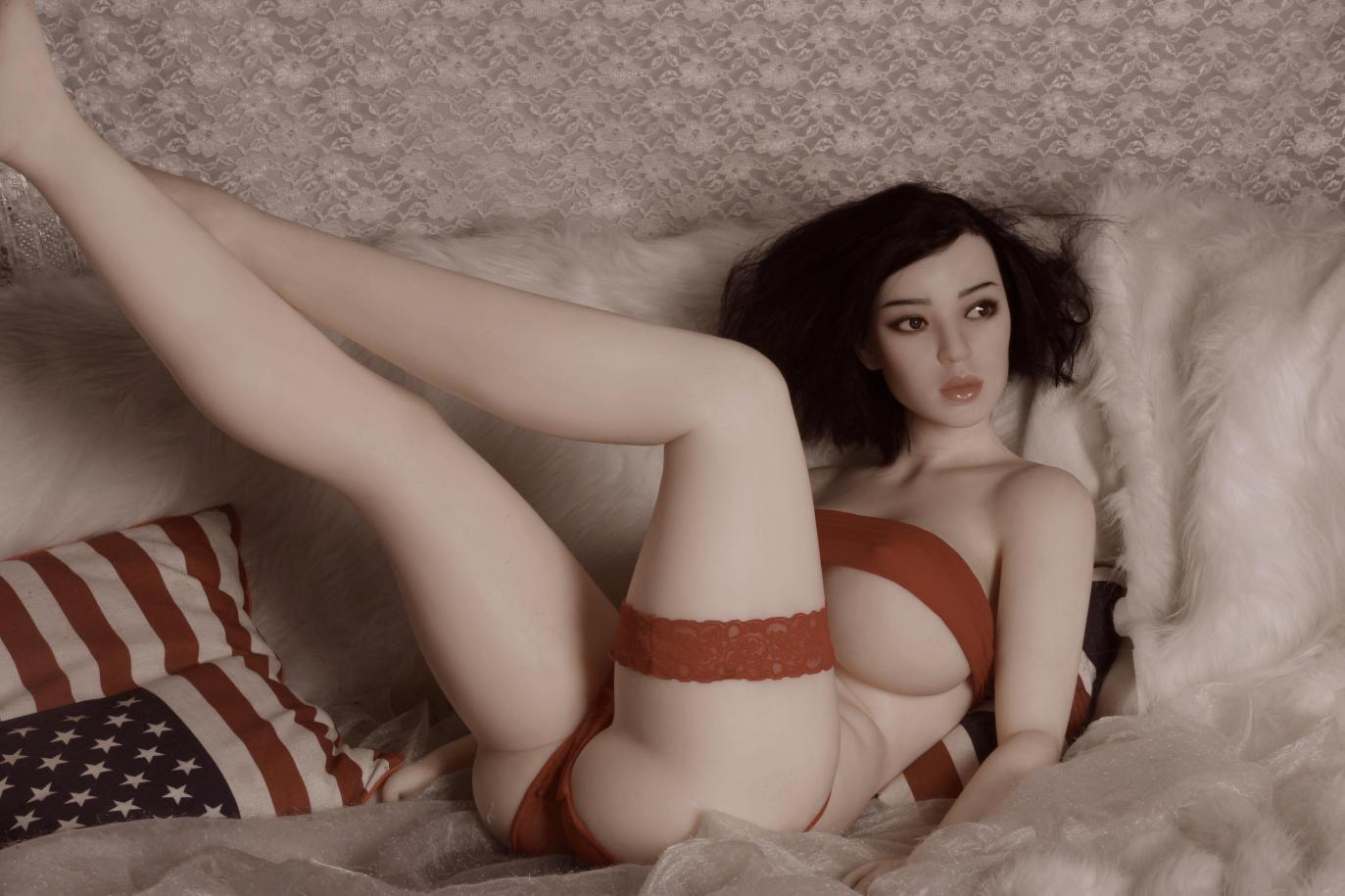 My experience of falling in love with a sex doll header image shows a full size, dark haired sex doll reclining on a bed, wearing red lingerie.