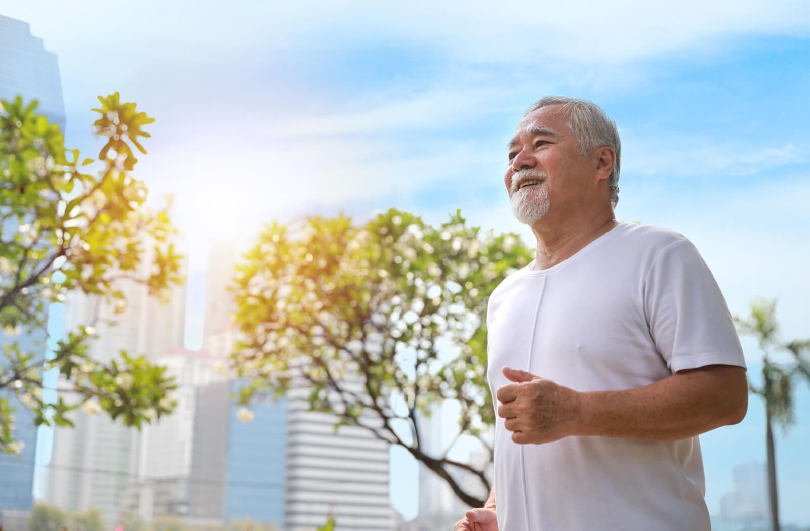 A senior man smiling while walking in a park.