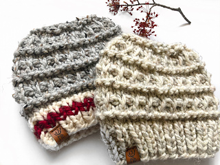 two textured knit messy bun beanies lying flat on white background