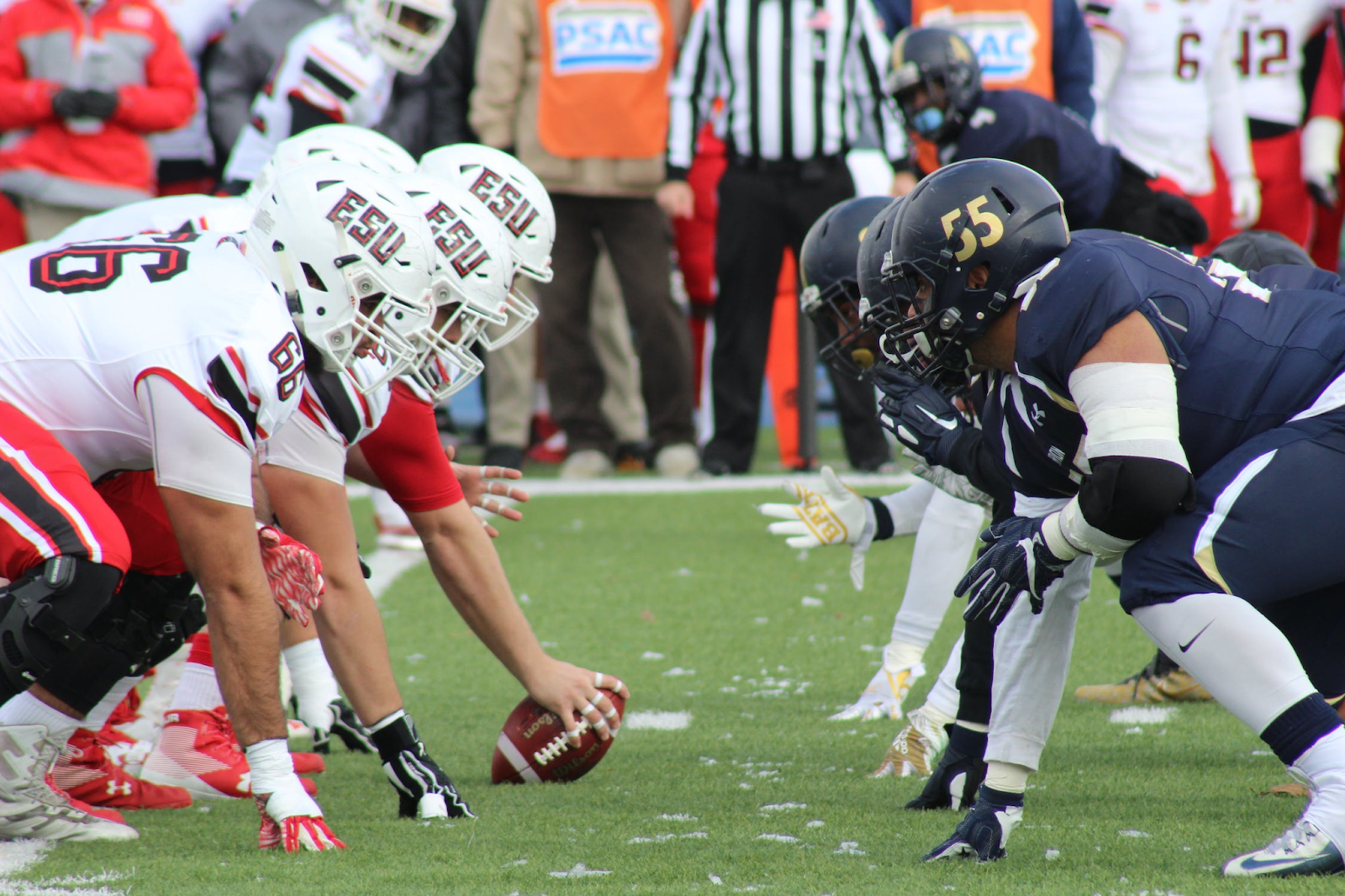 Football players assume positions at the line of scrimmage, poised for the snap of the ball