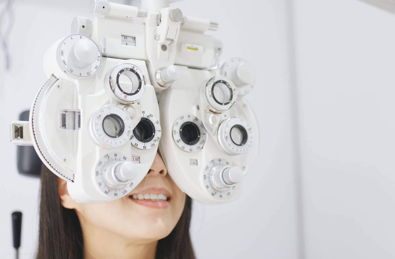 A woman sitting in an optometrist's office looking into a machine that tests her vision.