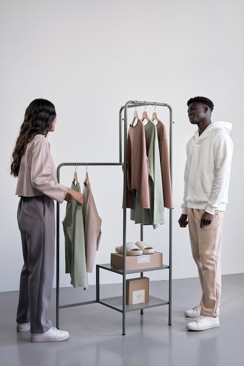 Free A Man and Woman Standing Near the Clothes Rack Stock Photo
