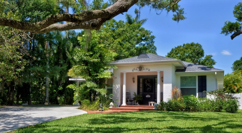 A white, single-story home in Bradenton River District with an ornate light fixture and rocking chair adorning the front porch.
