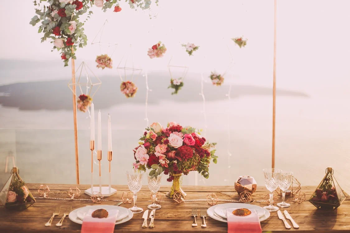 In this image a dining table is set up with flowers, bouquet, candles
