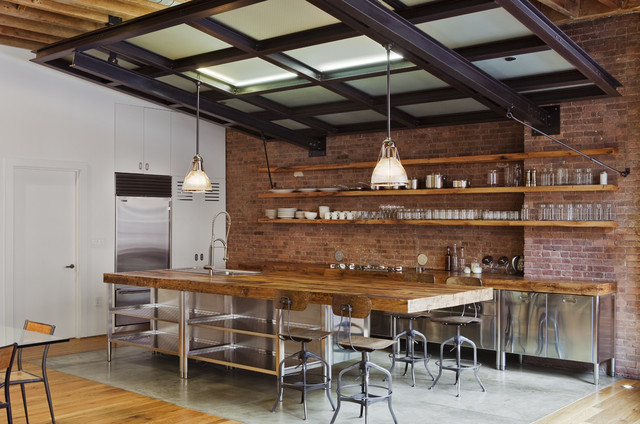 modern industrial kitchen features reclaimed wood salvaged from an old barn. The wood is used for the island, countertops, and three long floating shelves.
