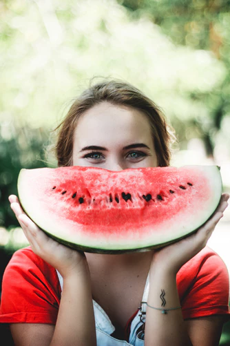 woman holding watermelon to face as a smile