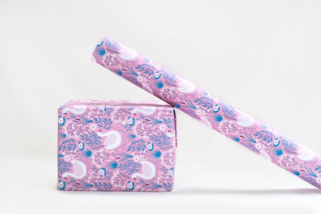 鳥と植物がデザインされたピンクの包装紙で包まれたプレゼント