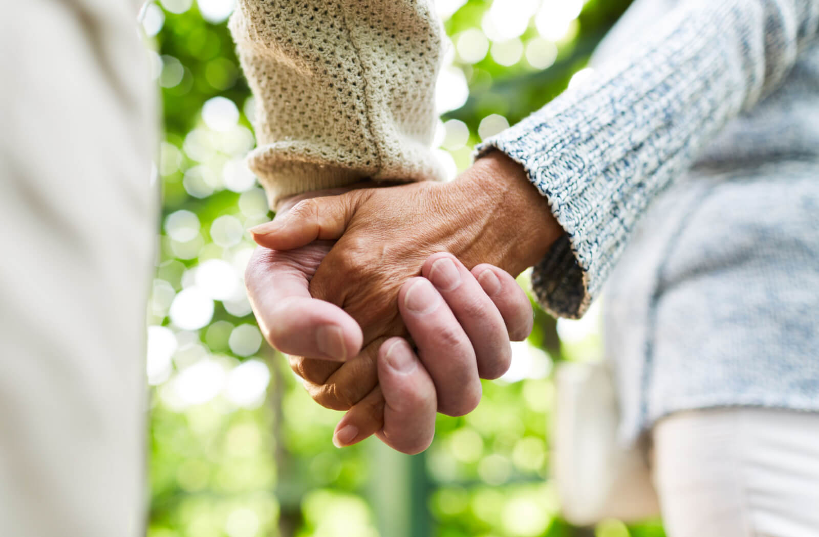two senior spouses hold hands
