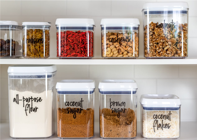 Dry goods organized in labeled plastic containers and arranged on shelves