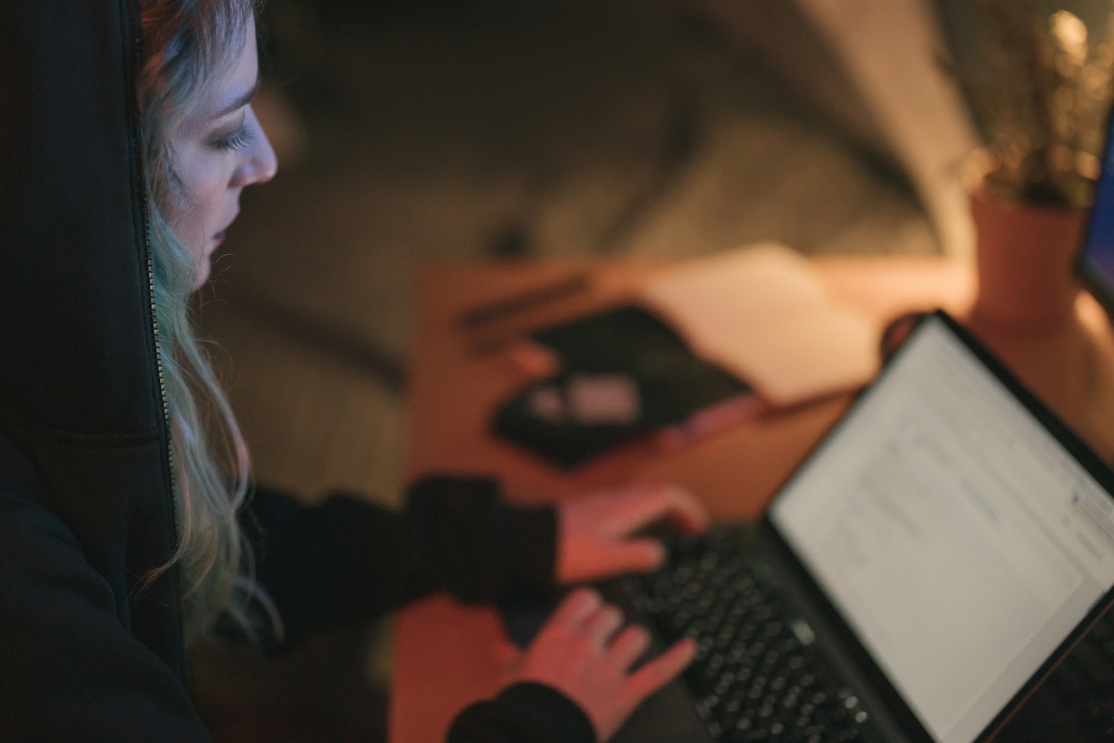 a woman in a hoodie studies text on a laptop