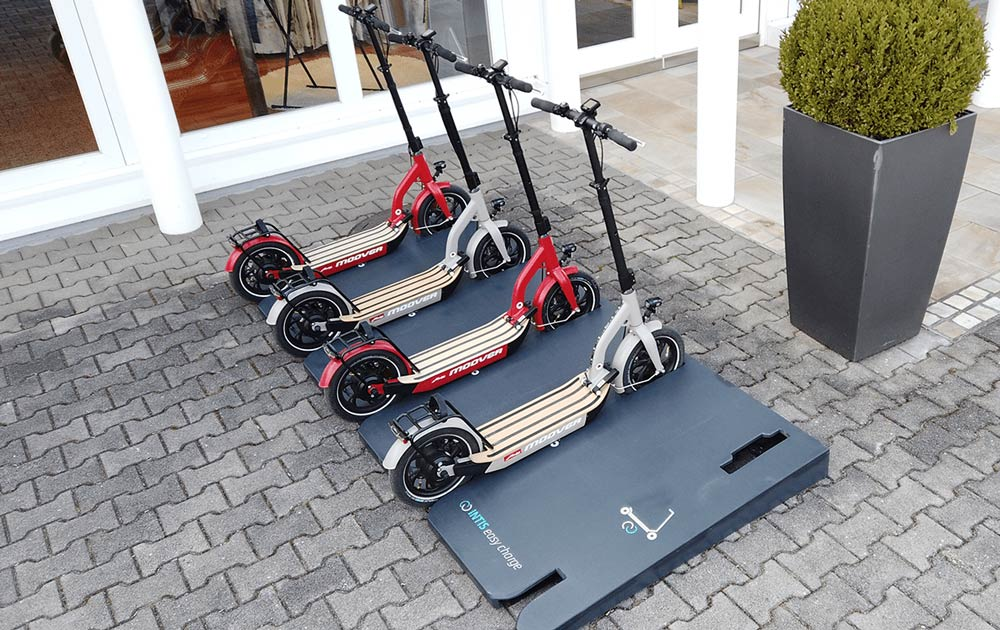 quatre trottinette electrique sur un parc de recharge