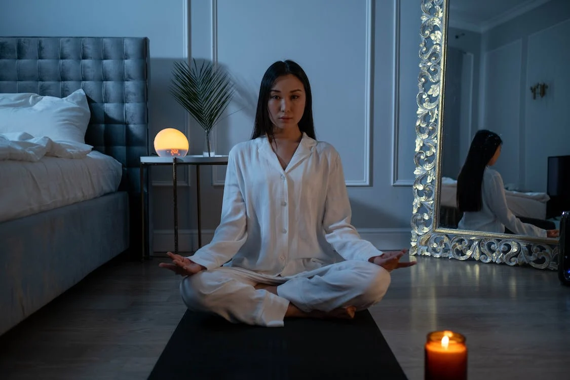 a woman in white robe meditating on the floor