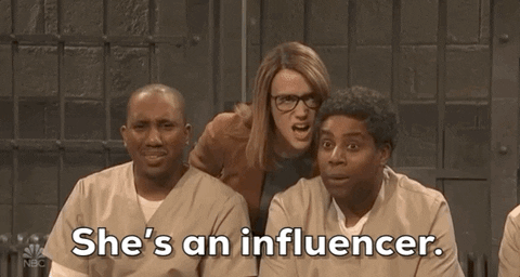 Giphy clip of three people gossiping while looking at someone and saying "She's an influencer". 