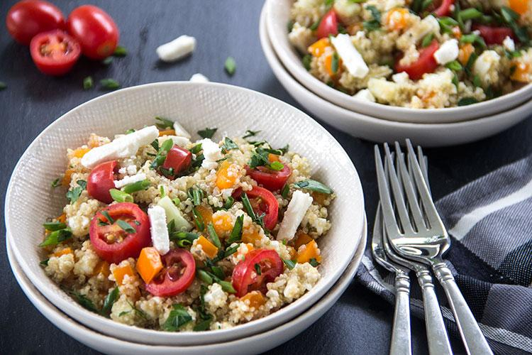 Fresh tomato and feta cheese salad with chopped herbs and a drizzle of olive oil on top.