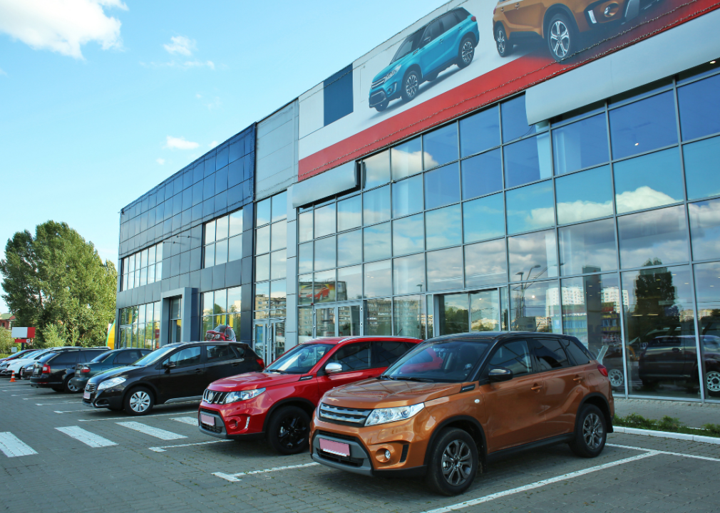 Used cars in front of glass dealership building.