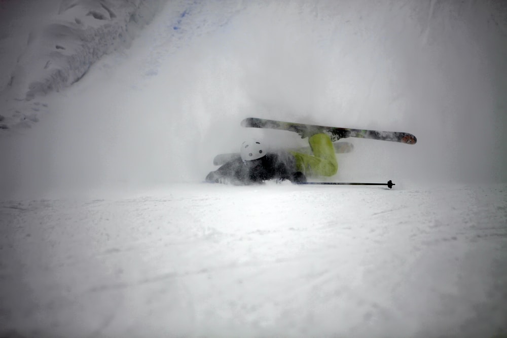 person in green jacket and black pants riding ski blades on snow covered ground during daytime