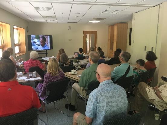 A group of people sitting in a room watching a television

Description automatically generated with medium confidence