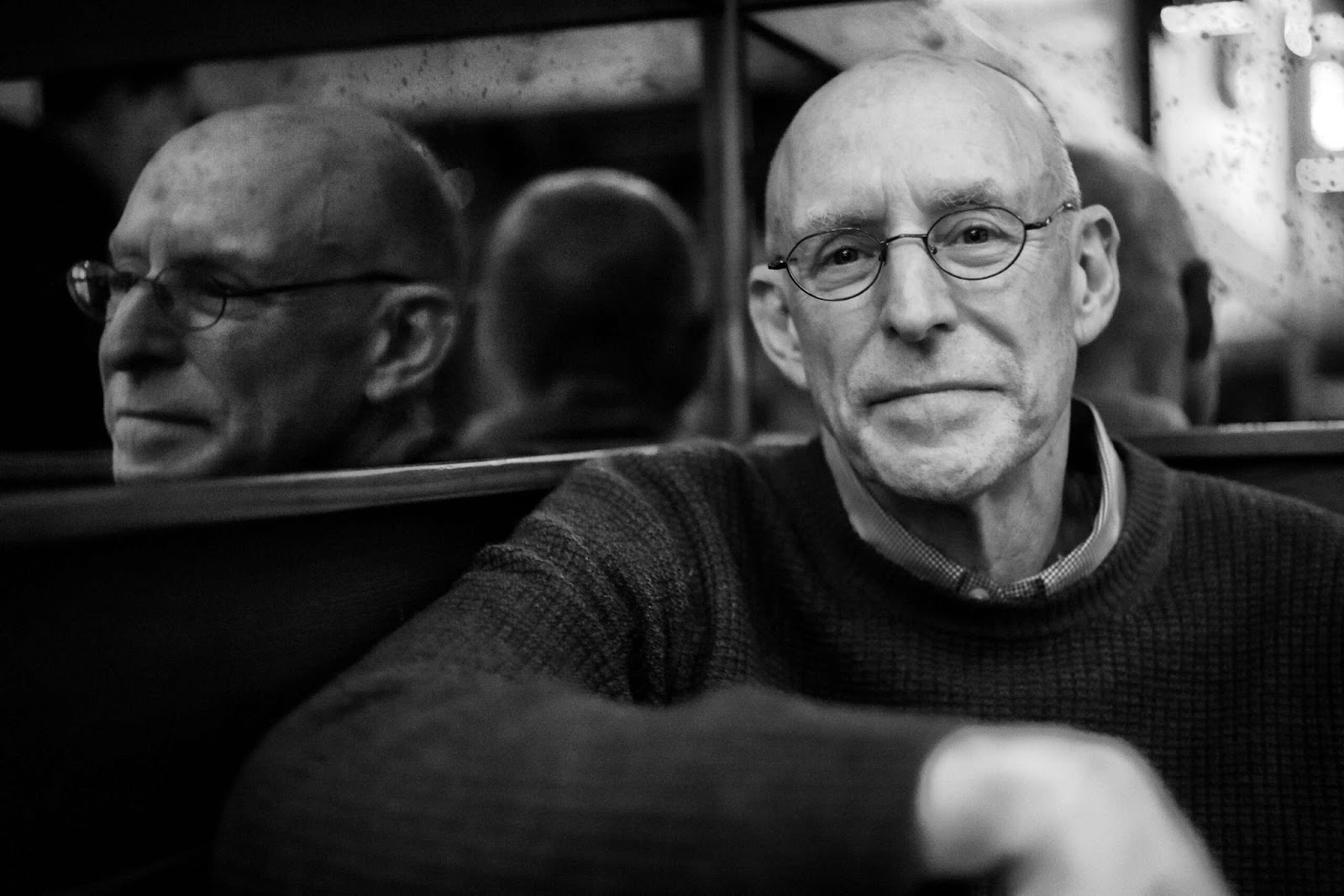 O escritor Michael Pollan sentado com sua imagem refletida ao lado, em foto PB
