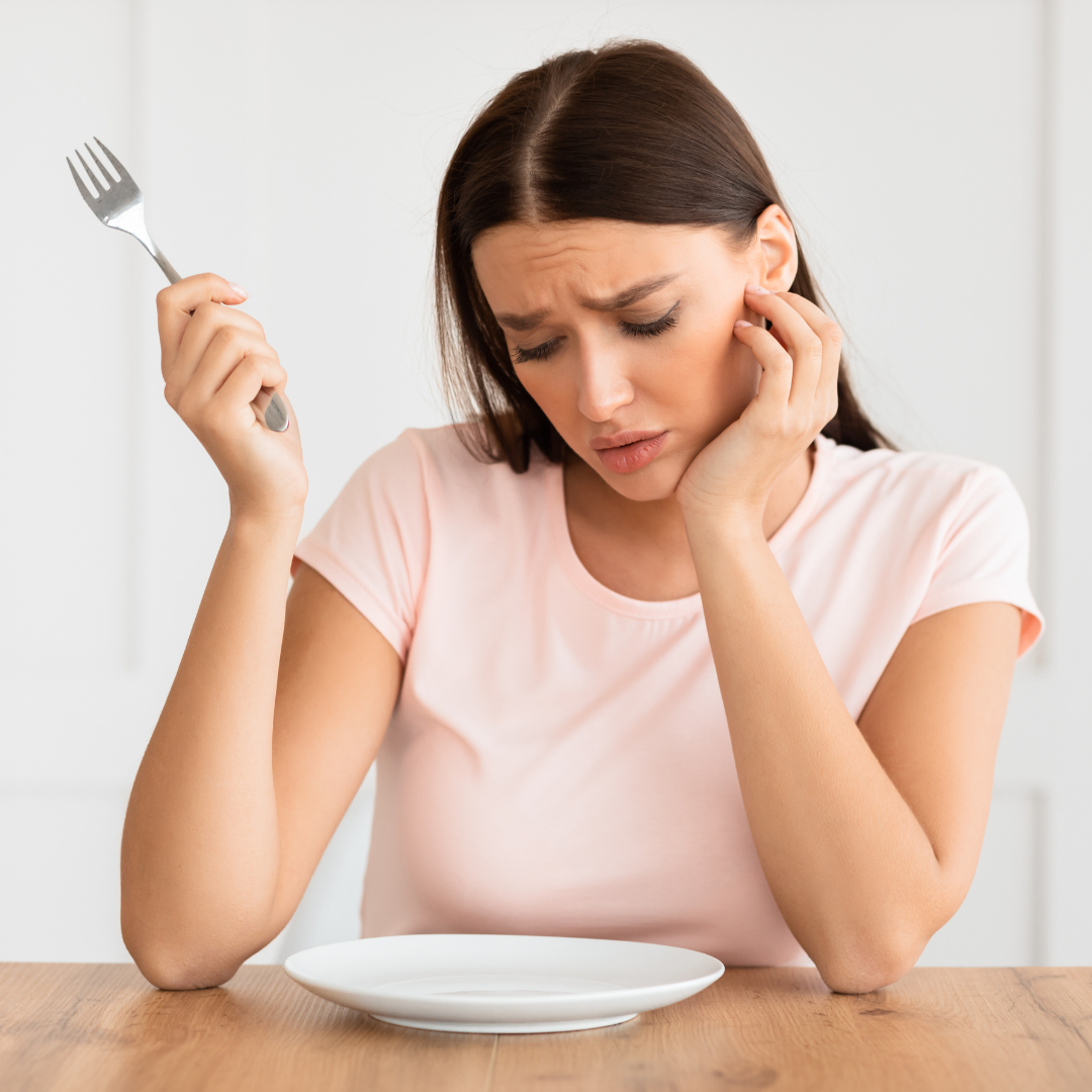 Hungry woman staring into an empty plate