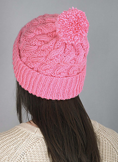 woman wearing a pink cable knit beanie with pom pom 