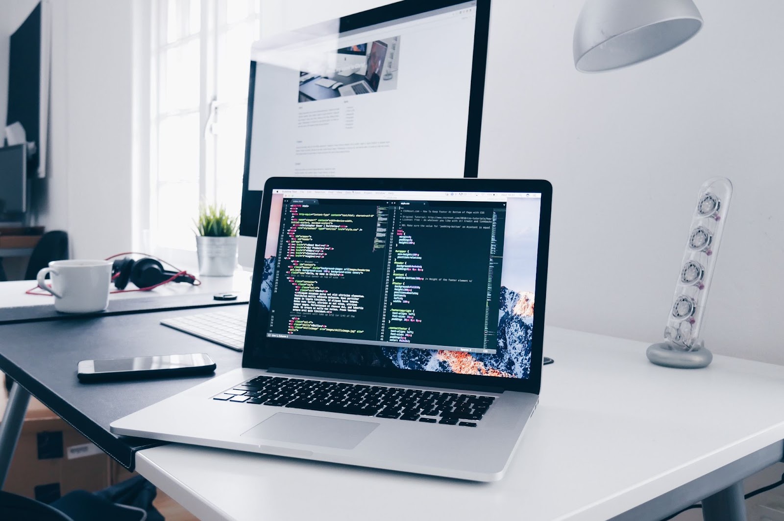 open-mac-book-laptop-on-white-desk-displaying-website-code