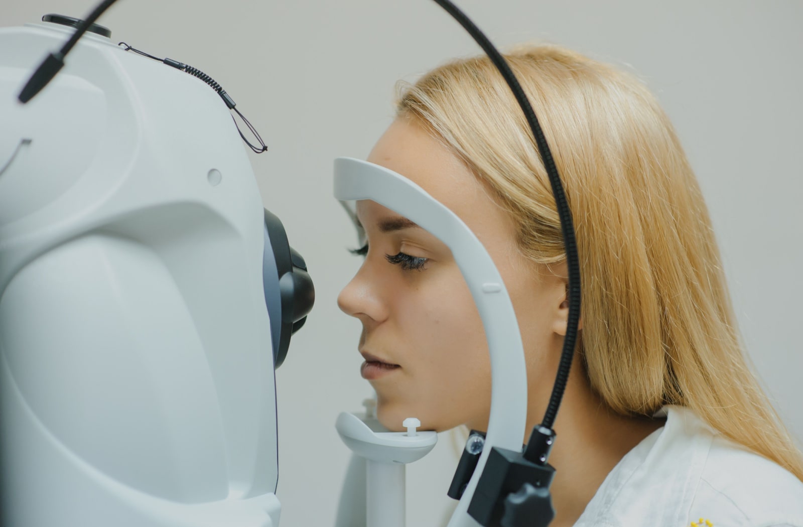 close up of a young female patient placing her head in Optical Coherence Tomography (OCT) equipment at the optometrists office