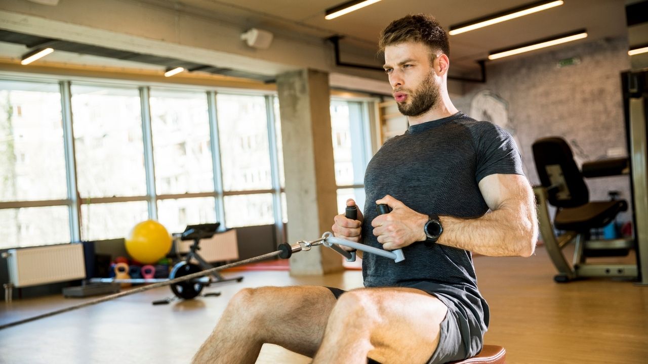 A man performs a seated cable rows exercise in the gym.