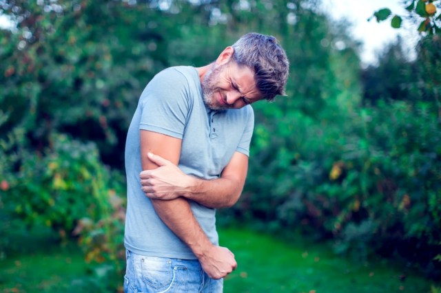 man with dark hair suffering from elbow pain outdoor