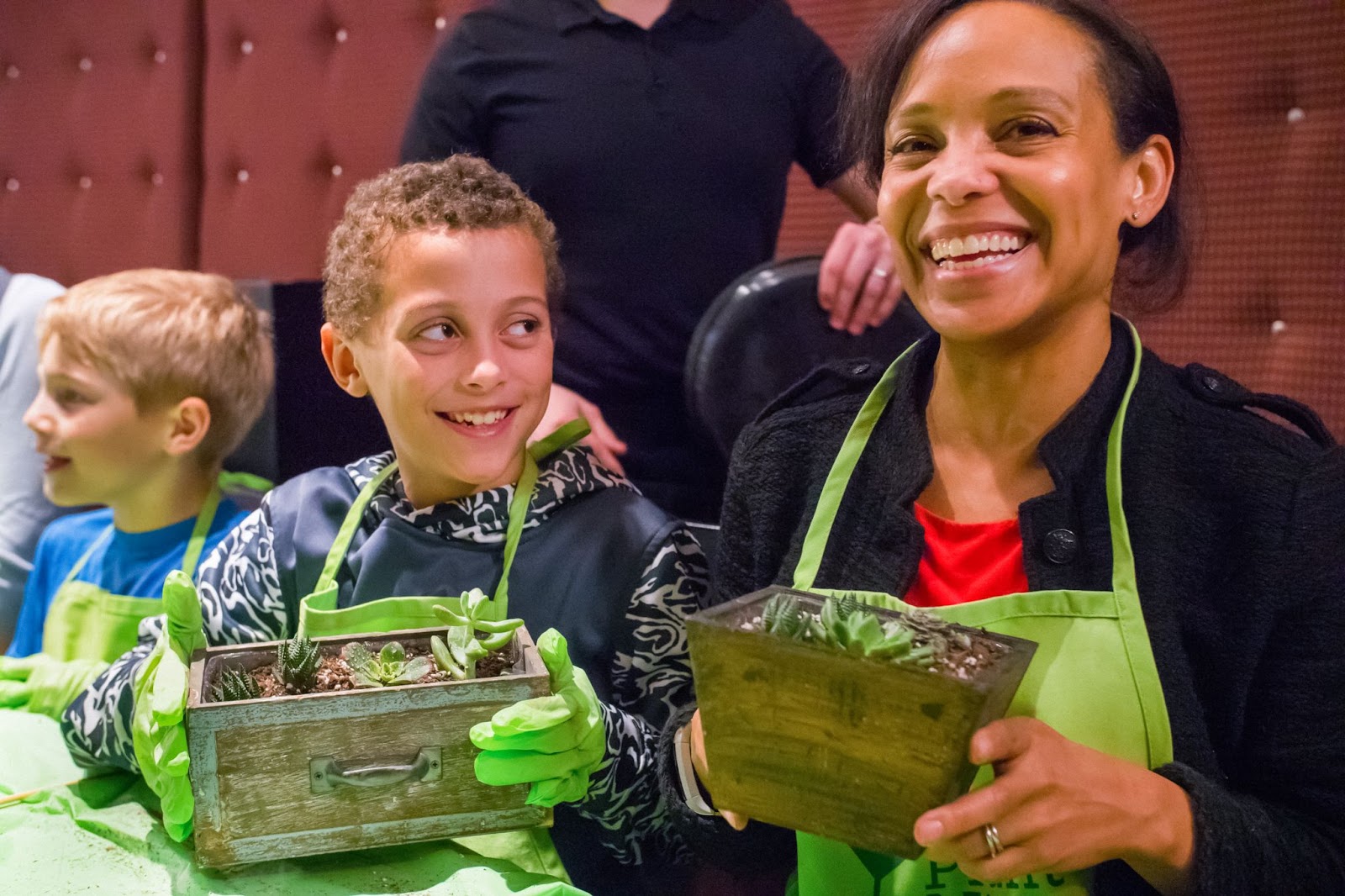 Mother and son smiling and holding up their finished Plant Nite terrariums.