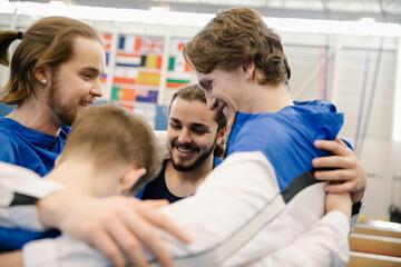 Male gymnasts in huddle in gymnasium