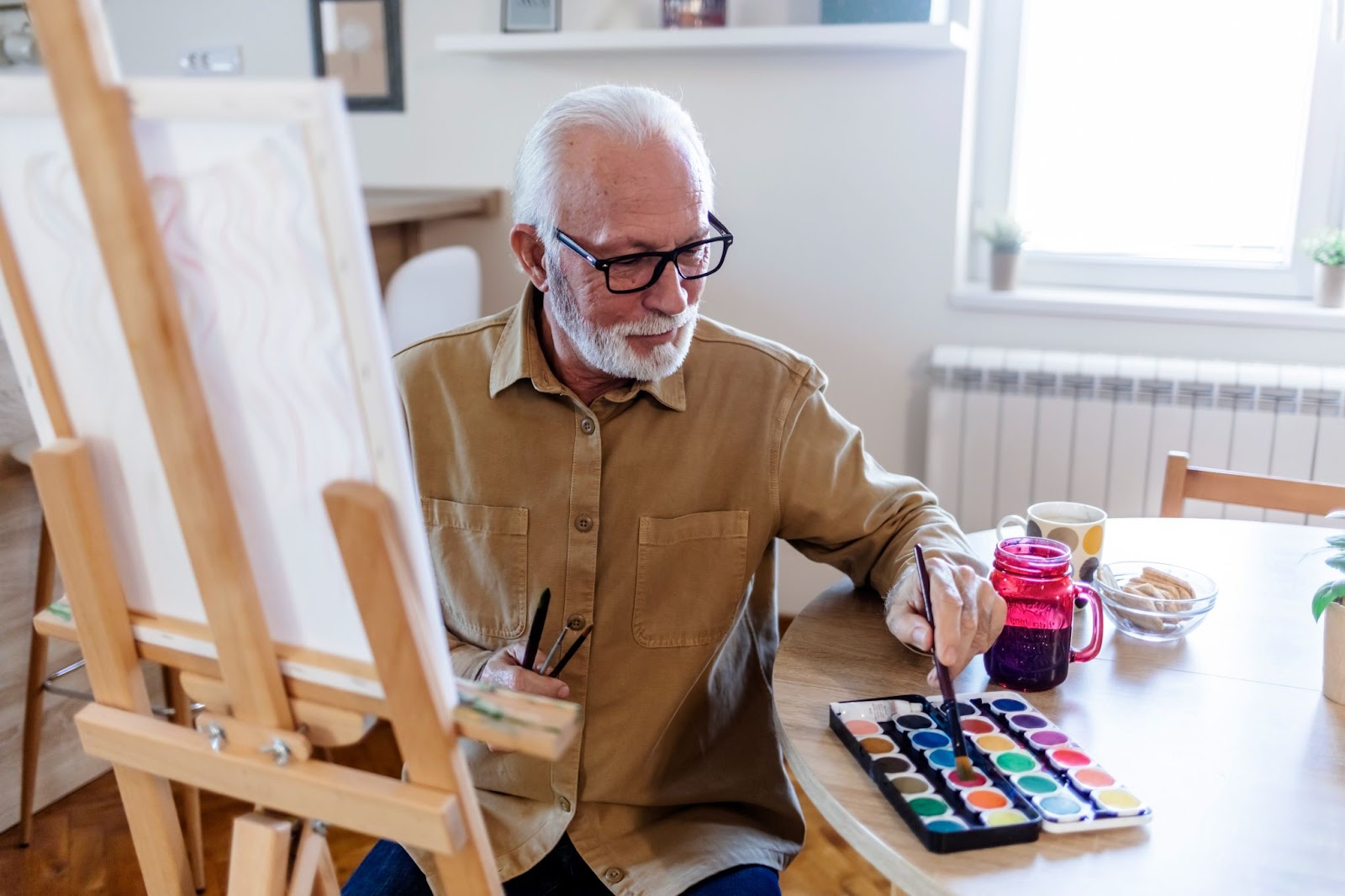 An elderly person engaged in the therapeutic activity of painting, expressing creativity and finding joy in their artistic pursuit.