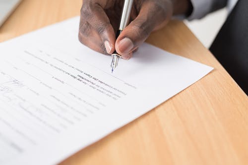 Person signing document with a silver fountain pen