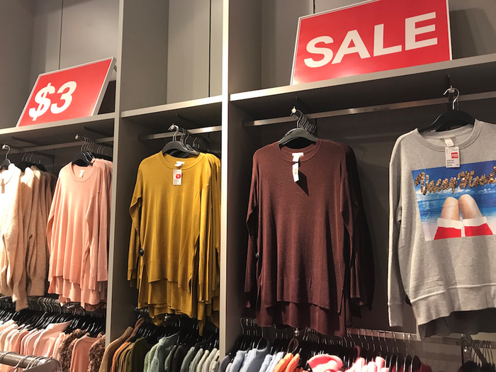 Fashion sale signs positioned above clothing racks in a store.