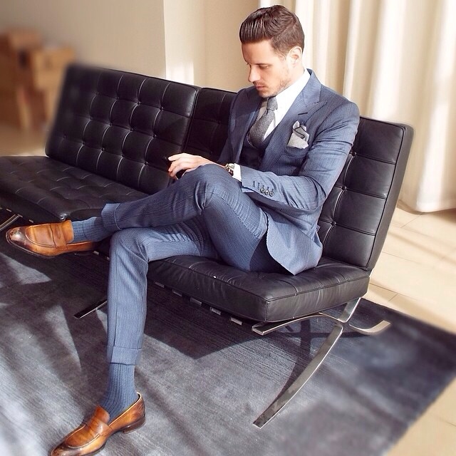 well dressed man in grey suit sitting on a leather couch