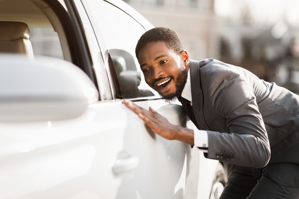 A man takes a look at the exterior of a used car to understand its worth