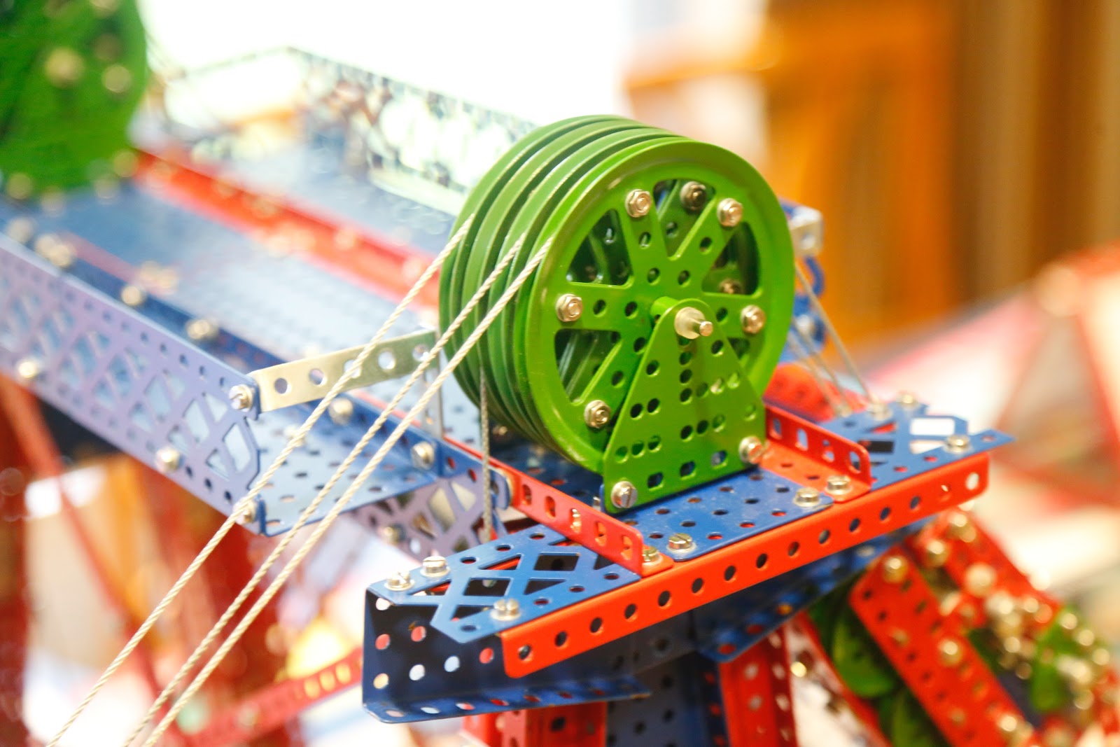 This is a close up view of a pulley and cables attached to a children's engineering toy that looks similar to the popular Erector Set.