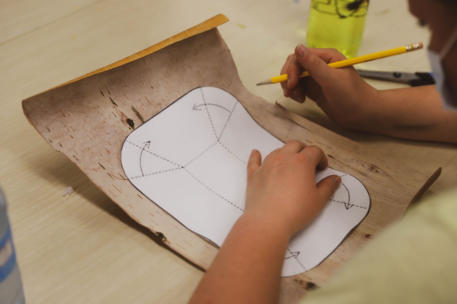 A woman traces a pattern of a birch bark basket