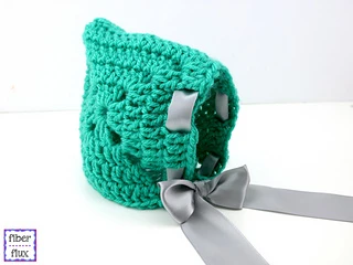 green baby bonnet with gray ribbon on white background