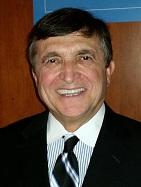 A person wearing a suit and tie smiling at the camera  Description automatically generated
