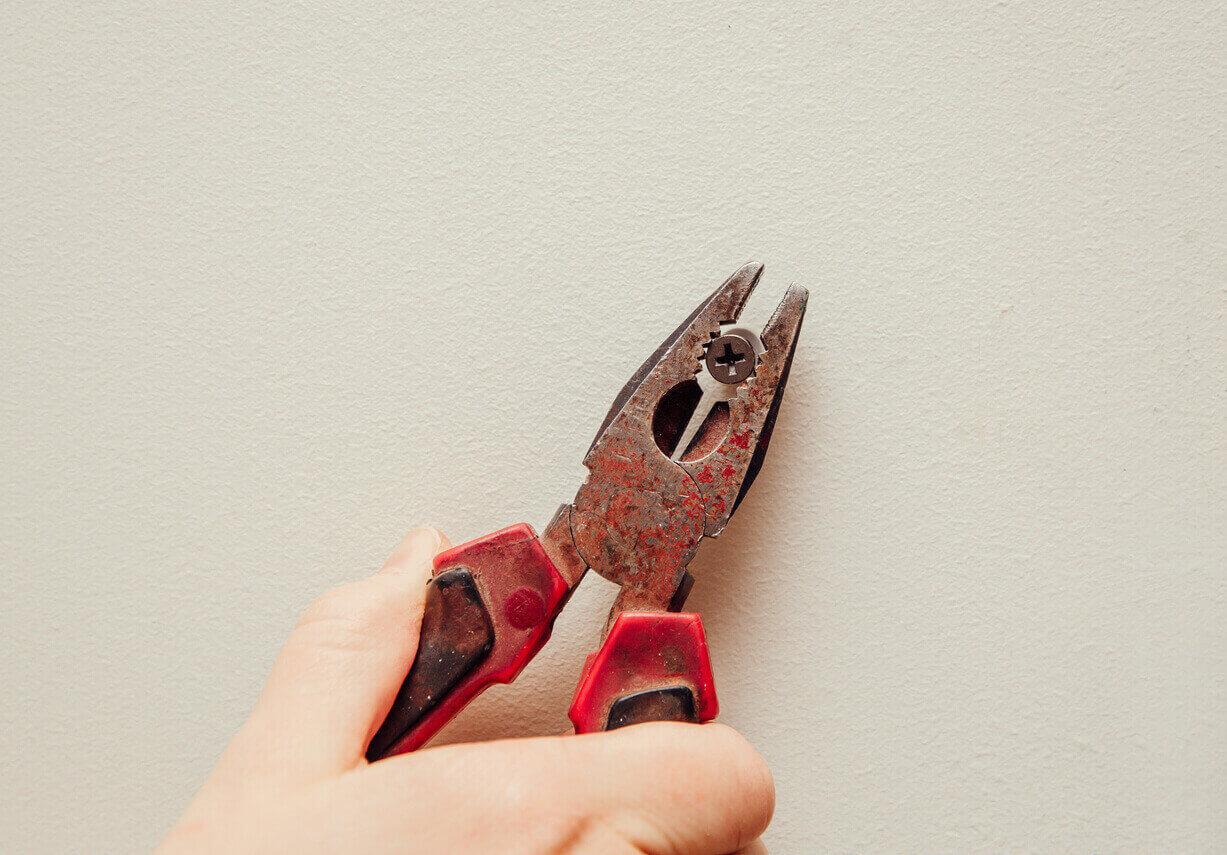 A hand holding a pliers

Description automatically generated