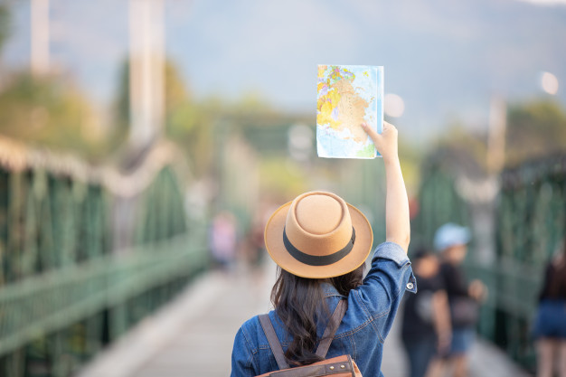 Femininos turistas na mão têm um mapa de viagem feliz. Foto gratuita