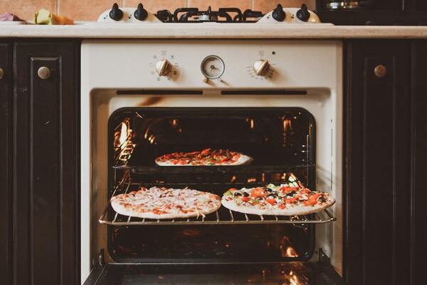 Foto de um forno aberto com 3 pizzas