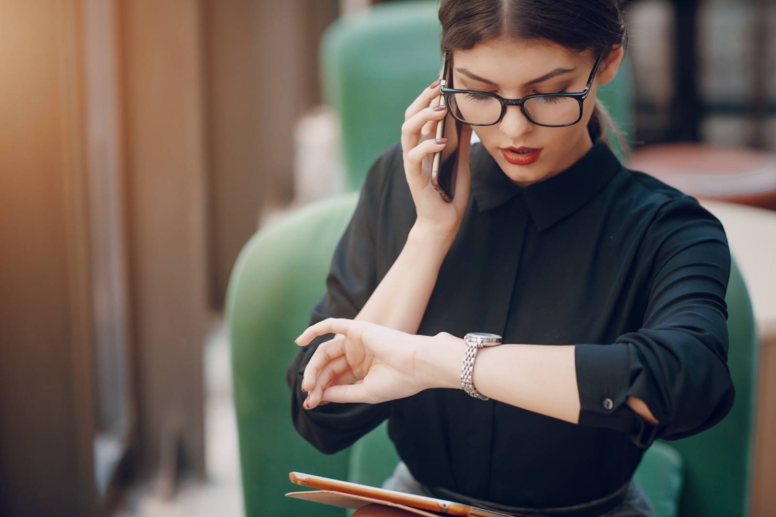 mulher no telefone e conferindo a hora  em um look com relógio preto