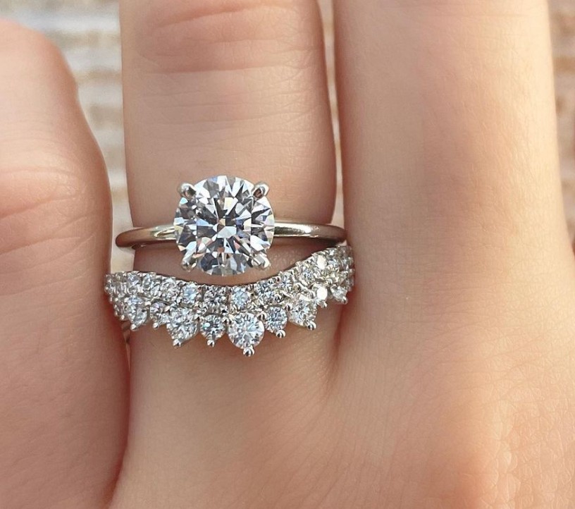 Alt: A decorative wedding band below a solitaire round cut diamond engagement ring